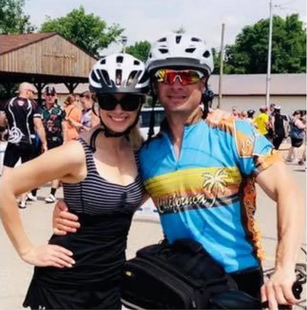 Loren and Ashley in cycling gear and helmets at a bike event